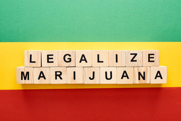 top view of wooden blocks with legalize marijuana lettering on Rastafarian flag background