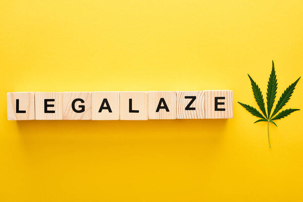 top view of marijuana leaf and legalize word on wooden blocks on yellow background
