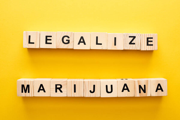 top view of wooden blocks with legalize marijuana lettering on yellow background