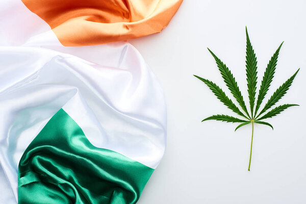 top view of green cannabis leaf near flag of Ireland on white background