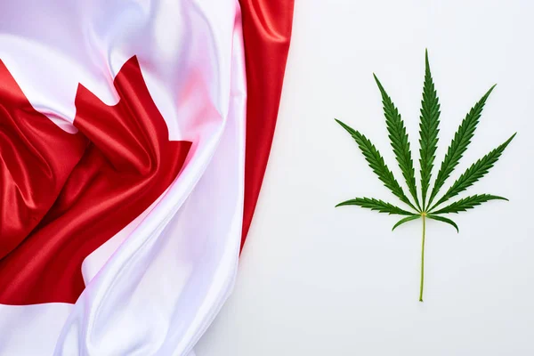白い背景にカナダの旗の近くに緑の大麻の葉のトップビュー — ストック写真