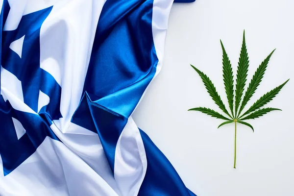 白い背景にイスラエルの旗の近くに緑の大麻の葉のトップビュー — ストック写真
