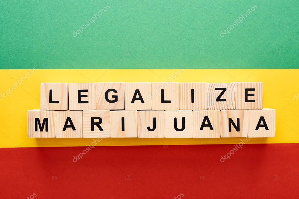 Top view of wooden blocks with legalize marijuana lettering on Rastafarian flag background