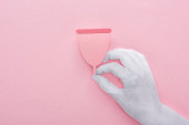 abgeschnittene Ansicht der weißen Hand mit rosa Papier Menstruationstasse auf rosa Hintergrund
