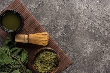 koyu taş masada bambu mat üzerinde çırpma teli ile geleneksel matcha çay üst görünümü