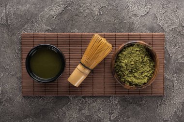 koyu taş masada bambu mat üzerinde çırpma teli ile matcha çay üst görünümü