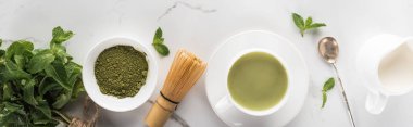 beyaz masa üzerinde yeşil matcha çay, nane ve süt ile düz yatıyordu
