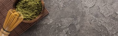 koyu taş masada bambu mat üzerinde çırpma teli ile kase matcha yeşil çay tozu üst görünümü