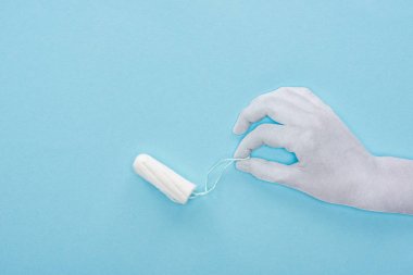 mavi arka plan üzerinde pamuk tampon tutan beyaz kağıt kesilmiş el üst görünümü