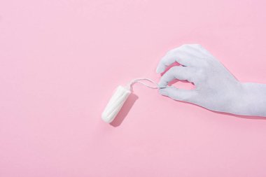 pembe arka plan üzerinde pamuk tampon tutan beyaz kağıt kesilmiş el üst görünümü