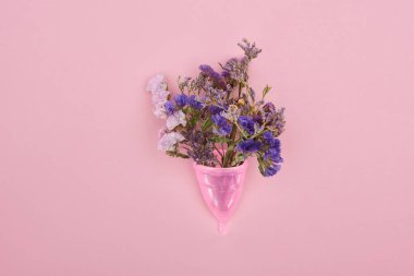 top view of pink plastic menstrual cup with wildflowers isolated on pink clipart