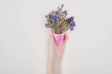 gri izole kır çiçekleri ile pembe adet fincan tutan kadının kırpılmış görünümü