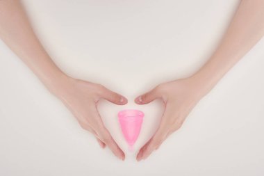 cropped view of female hands near pink plastic menstrual cup isolated on grey clipart