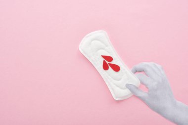 pembe arka plan üzerinde kan damlaları ile beyaz sıhhi peçete tutan el kırpılmış görünümü