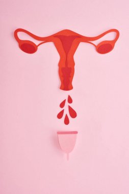 top view of red paper cut female reproductive internal organs with blood drops and menstrual cup on pink background clipart