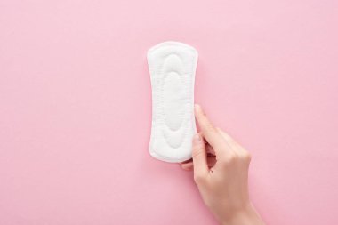 pembe arka plan üzerinde beyaz sıhhi peçete tutan kadının kırpılmış görünümü