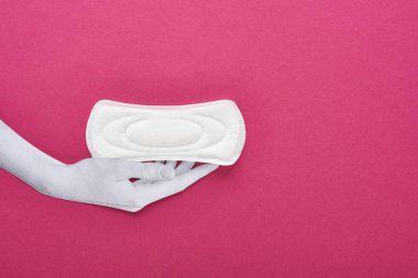 top view of paper cut white hand and white sanitary napkin on purple background clipart
