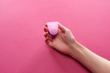 mor arka plan üzerinde kan ile plastik adet fincan tutan kadının kısmi görünümü