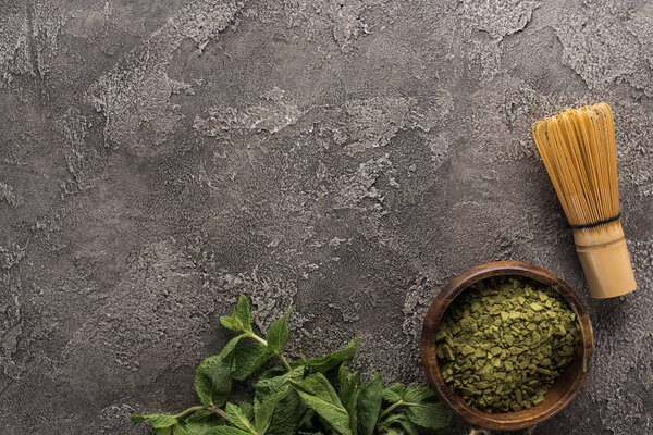 вид на зеленый чай маття, венчик и мяту на темном каменном столе
