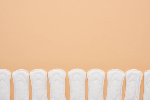 row of white cotton sanitary towels isolated on beige