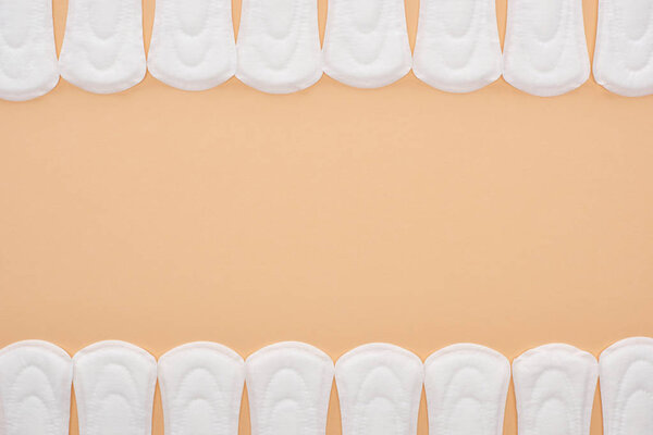 frame of white cotton sanitary towels isolated on beige with copy space