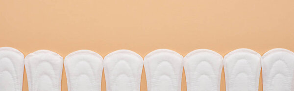 flat lay with white cotton sanitary towels in row isolated on beige, panoramic shot