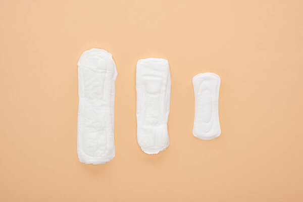 top view of three white cotton sanitary towels isolated on beige