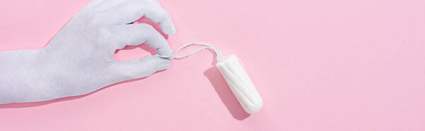 top view of white paper hand holding cotton tampon on pink background, panoramic shot