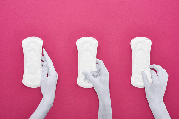 top view of paper cut white hands and white sanitary napkins on purple background