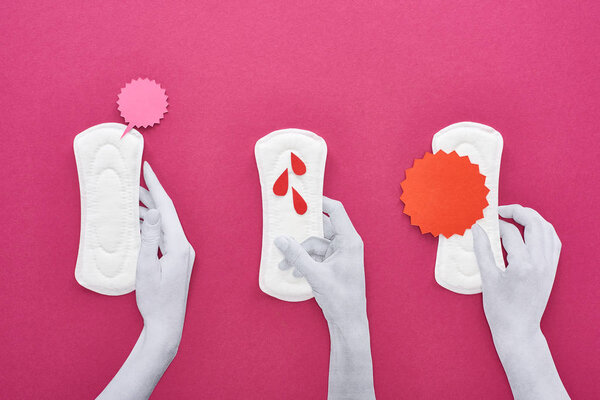 top view of paper cut white hands and white sanitary napkins with cards and blood drops on purple background