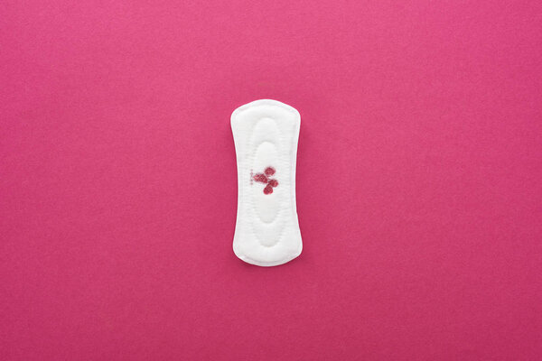 верхний вид белой гигиенической салфетки с кровью на фиолетовом фоне
