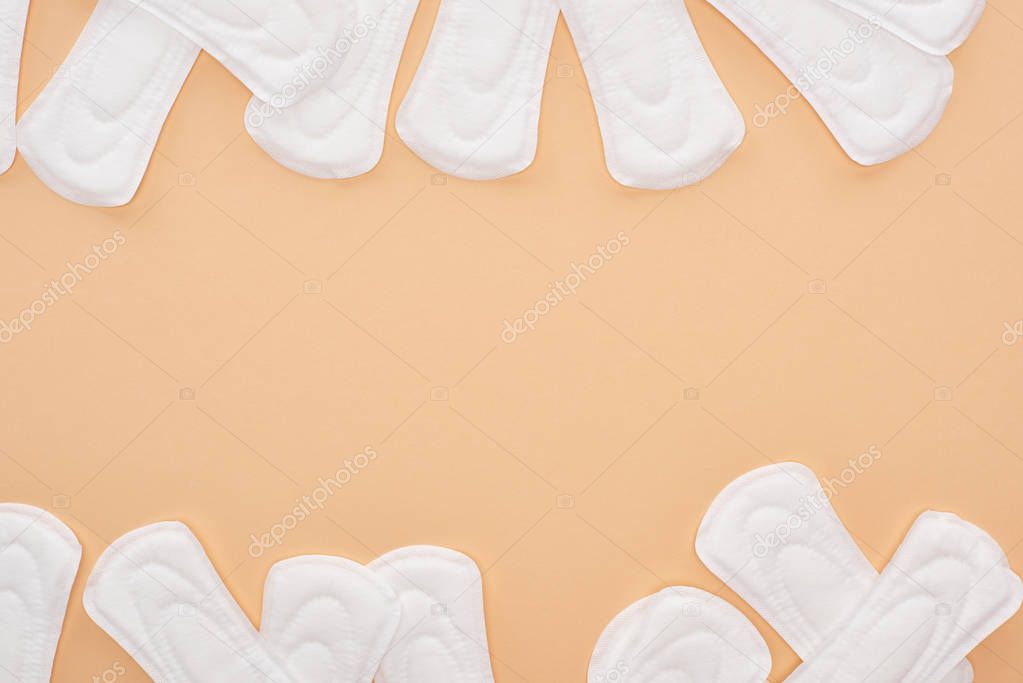 top view of scattered white cotton sanitary towels isolated on beige