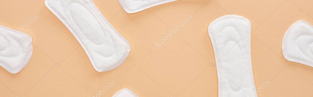 top view of white cotton sanitary napkins scattered isolated on beige, panoramic shot