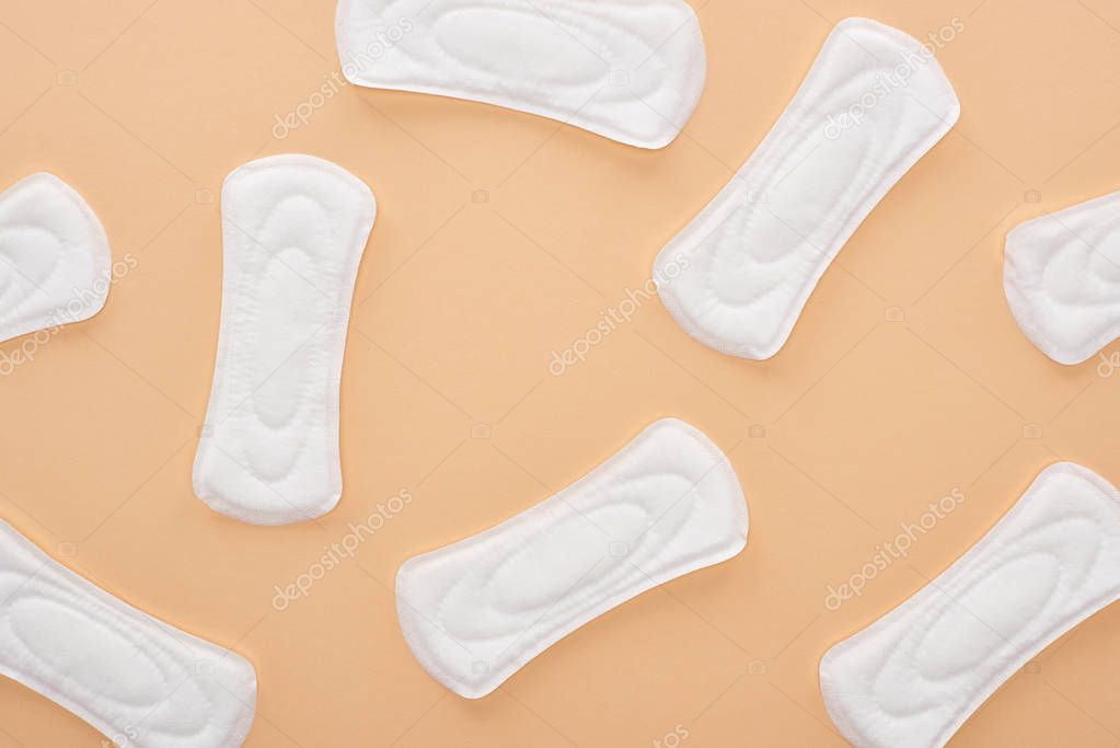 top view of white cotton sanitary napkins scattered isolated on beige