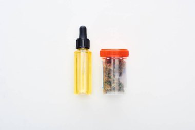 beyaz arka plan üzerinde şişe cbd yağı yakınında plastik kapta esrar ile düz yatıyordu
