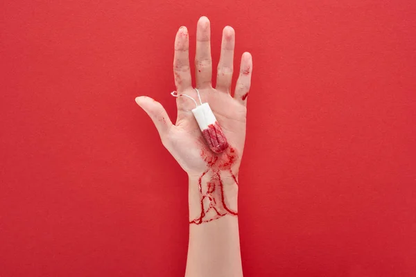 赤い背景に血を持つタンポンを持つ女性のトリミングされたビュー — ストック写真