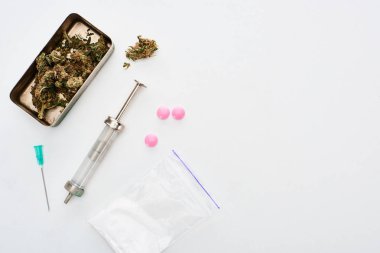 top view of marijuana buds, heroin, lsd and syringe on white background clipart