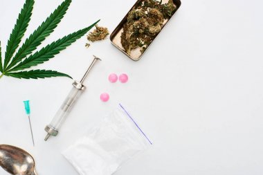 top view of marijuana buds, cannabis leaf, spoon, heroin, lsd and syringe on white background clipart