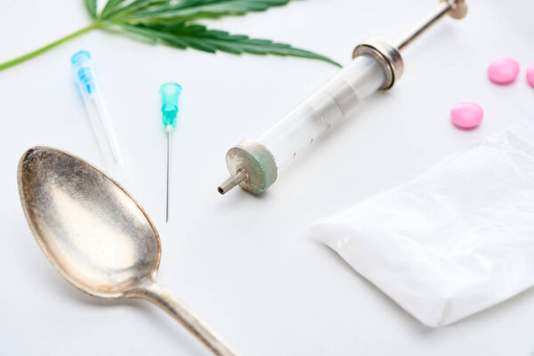 крупный план листьев конопли, серебряной ложки, шприца, героина и ЛСД
 