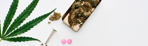 вид сверху на бутоны марихуаны, листья конопли, ЛСД и шприц на белом фоне, панорамный снимок
