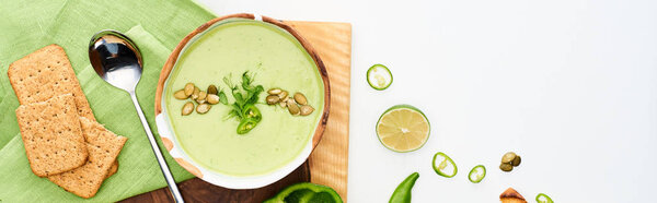 top view of delicious creamy green vegetable soup served on wooden cutting board isolated on white, panoramic shot