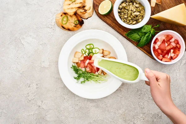 新鮮な食材を使用した木製のまな板の近くで緑のクリーミーなスープを調理する女性のトリミングビュー — ストック写真