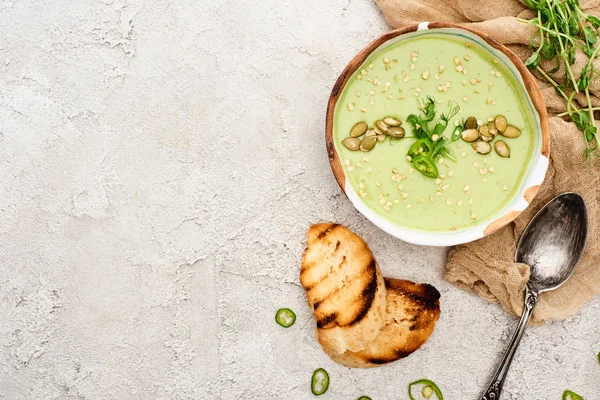 Top view of tasty green creamy soup with croutons and sprouts on textured grey background with rustic cloth — Stock Image Top View Tasty Green Creamy Soup Croutons Sprouts Textured Grey Stock Picture