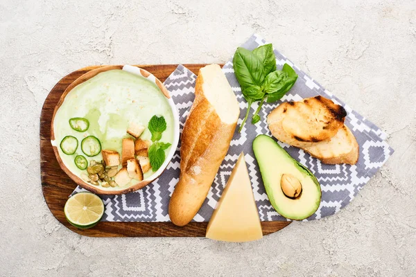 Top view of green vegetable creamy soup on wooden chopping board with napkin and ingredients — Stock Image Top View Green Vegetable Creamy Soup Wooden Chopping Board Napkin Royalty Free Stock Photos