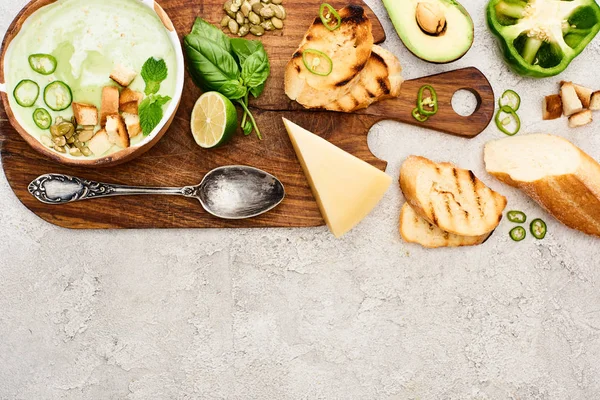 Top view of green vegetable creamy soup on wooden chopping board on textured surface — Stock Image Top View Green Vegetable Creamy Soup Wooden Chopping Board Textured Stock Picture