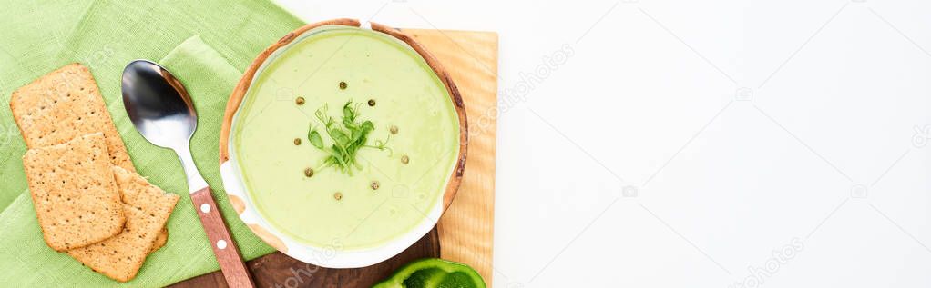 top view of delicious creamy green soup served with crackers isolated on white, panoramic shot