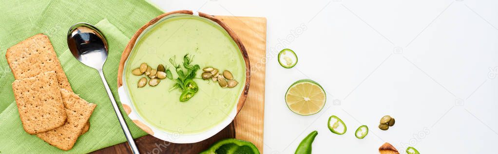 top view of delicious creamy green vegetable soup served on wooden cutting board isolated on white, panoramic shot