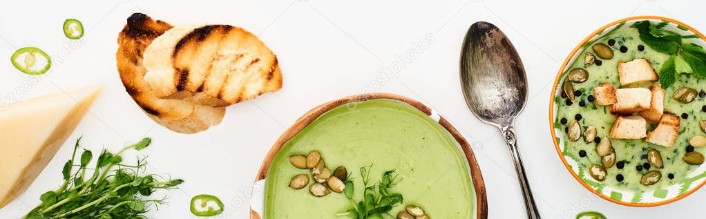 top view of delicious creamy green vegetable soup with sprouts, grilled croutons and cheese isolated on white, panoramic shot