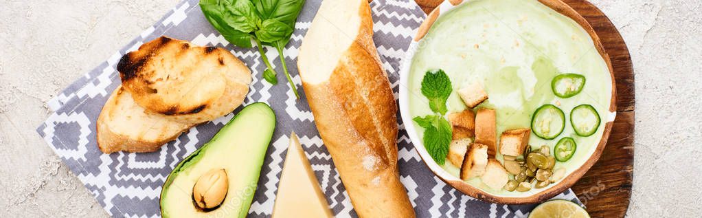 Panoramic shot of green vegetable creamy soup on wooden chopping board with napkin and ingredients — Stock Image Panoramic Shot Green Vegetable Creamy Soup Wooden Chopping Board Napkin Stock Photo