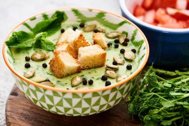 bowl of delicious green vegetable creamy soup with croutons, black pepper and pumpkin seeds clipart